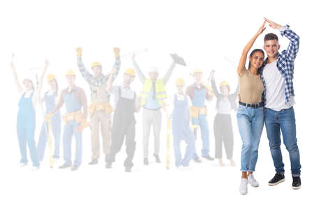 Happy young couple holding hand over the head showing house roof sign and happy construction workers...