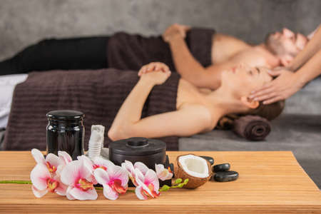 Beautiful couple relaxing together at spa center at beauty treatment massage, orchid flowers coconut and stonesの写真素材