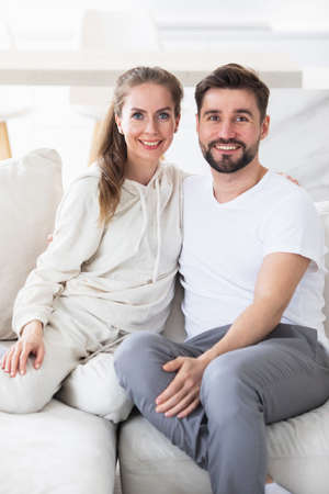 Portrait of mid adult couple relaxing in living room and smiling, looking at cameraの写真素材