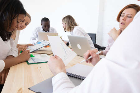 Confident businessmen and businesswomen sitting and working. Business people sitting around the desk...