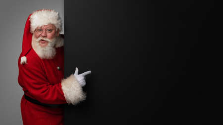 Santa Claus pointing at black paper billboard with copy space for textの写真素材