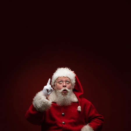 Full length portrait of Santa Claus pointing up to background with copy space for textの写真素材