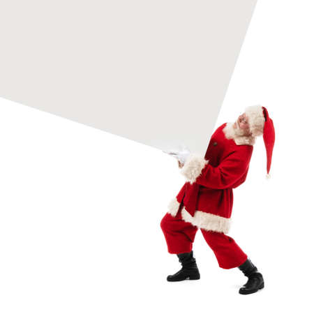 Santa Claus holding big heavy banner isolated on white background with copy space for textの写真素材