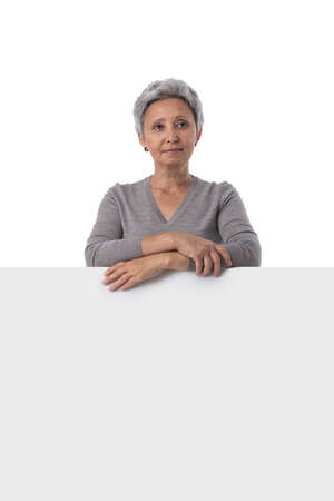 Mature asian woman is holding empty text board over white background and showing thumb upの写真素材
