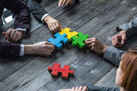 Diverse team people assembling jigsaw puzzle, multiracial group of black and white colleagues engaging in teamwork finding business solution, corporate unity teambuilding concept, top viewの写真素材