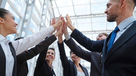Happy successful multiracial business team giving a high fives gesture as they laugh and cheer their...