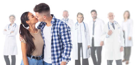 Happy couple kissing, team of doctors on background, fertility clinic counseling, reproductive issues conceptの写真素材