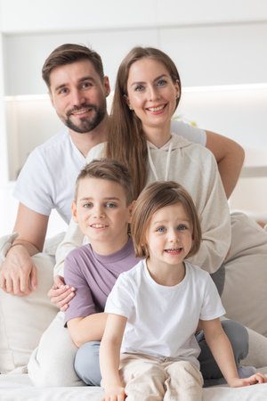 Happy family of parents with children sitting together on sofa at homeの写真素材