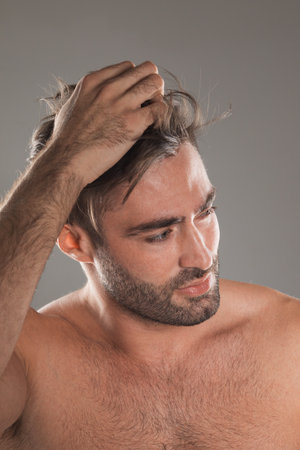 Closeup photo of macho man guy hold hand touch perfect neat hairstyle naked torso masculine body groomed appearance gray backgroundの写真素材