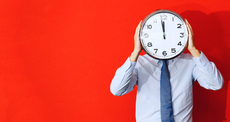 Man with wall clock on red background, deadline concept