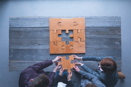 Finally finding a solution, business team putting last piece of puzzle at office meetingの写真素材