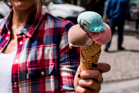 Girl Holding ice cream in the cone. Summer Concept.