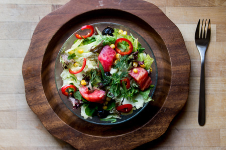 Fresh salad with tomatoes and olive oil on a wooden trayの写真素材