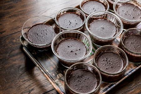 Homemade Chocolate Puddings in glass cups on wooden surfaceの写真素材