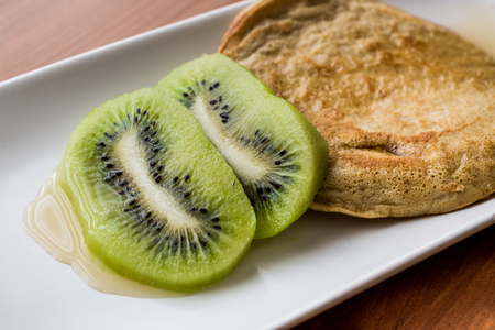Pancake with kiwi and maple syrup (made with organic flour) homemade product.の写真素材