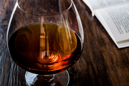 Glass of Cognac with a book on wooden surface. Beverage Concept.の写真素材