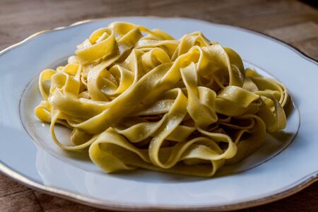 Plain Tagliatelle Pasta in white plate. Organic Spaghetti.
