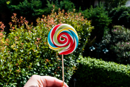 Holding Colorful Rainbow Lollipop. kids concept.