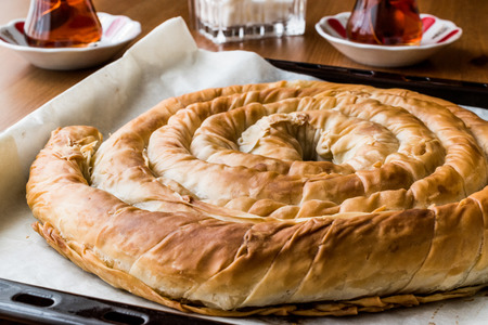 Round Borek in tray / Greek Cheese pie on wooden surfaceの写真素材