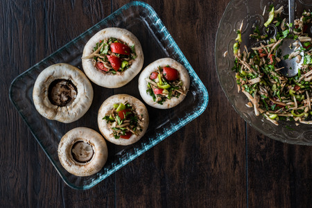 Mushrooms stuffed with vegetables before cooking on a wooden surface.の写真素材