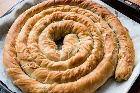 Round Borek in tray / Greek Cheese pie on wooden surfaceの写真素材