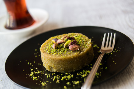 Turkish Dessert irmik helvasi / semolina with pistachio powder and tea.の写真素材