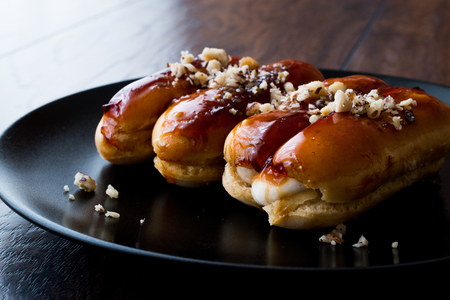 Caramel Eclairs with Hazelnut and cream in black plate. Dessert Concept.の写真素材