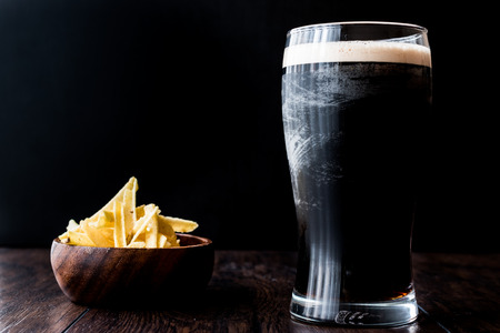 Dark Beer with snacks potato chips on wooden surface. Beverage Concept.の写真素材