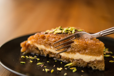 Turkish Traditional Dessert Ekmek Kadayifi / Bread Pudding on a wooden surface.
