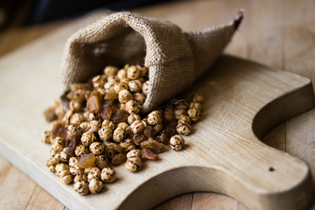 Roasted chickpeas in sack on wooden surface.の写真素材