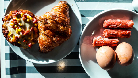 Croissant breakfast with mini pizza, sausage and eggs for breakfastの写真素材