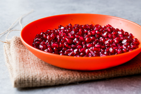 Organic Fresh Pomegranate Seeds in Red Bowl with Blue Background. Organic Food.の写真素材