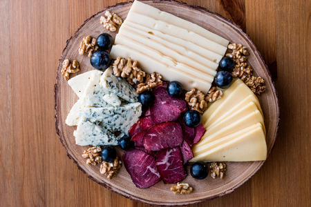 Cheese Plate with smoked meat, walnuts and grapes on wooden surface. Organic Food.の写真素材