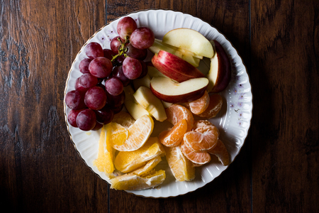 Fruit Plate with Purple Grape, Orange, Mandarin and Apple. Dark Moody. Organic Food.の写真素材