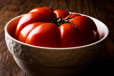 Big Tomato in bowl on wooden surface. Organic Food.の写真素材