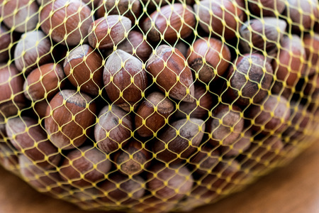 Hazelnuts in the net on wooden surfaceの写真素材