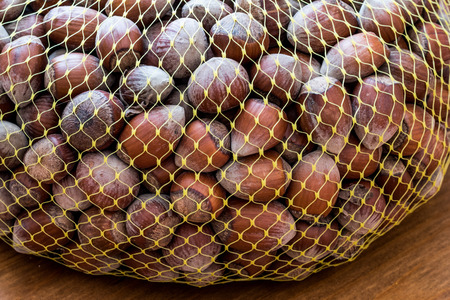 Hazelnuts in the net on wooden surface