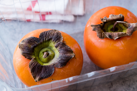 Fresh Persimmon Fruits in Plastic Box. Organic Food.の写真素材