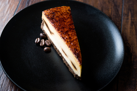 Coffee Cheesecake on Black Plate with Dark Wooden Surface. Dessert.の写真素材
