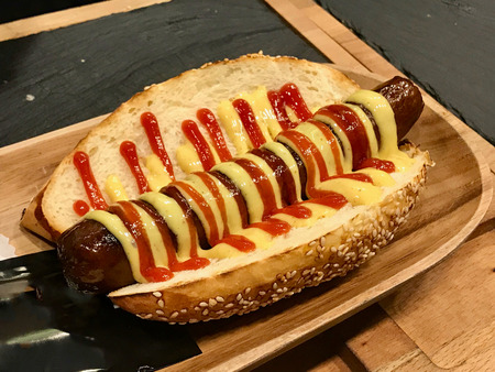 Barbecue Grilled Hot Dog with Yellow Mustard and Ketchup in Baguette Bread. Fast Food.