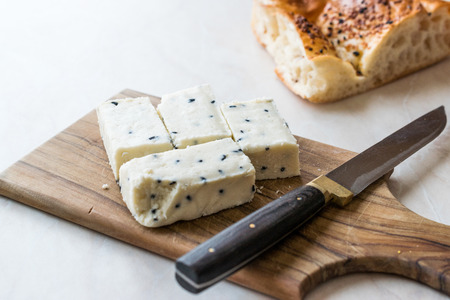 Turkish Feta Cheese with Black Cumin (Sesame) Seeds on Wooden Surface with Knife. Traditional Organic Food.