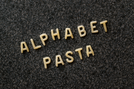 Raw Alphabet Pasta is Written with Letters  on Granit Grey Surface. Uncooked Organic Food.の写真素材