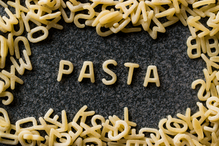 Raw Alphabet Pasta is Written with Letters  on Granit Grey Surface. Uncooked Organic Food.の写真素材