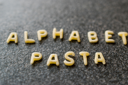 Raw Alphabet Pasta is Written with Letters  on Granit Grey Surface. Uncooked Organic Food.の写真素材