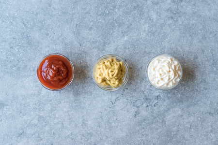 Set of Three Classic Sauce Ketchup, Mayonnaise and Mustard in Small Glass Bowls.の写真素材