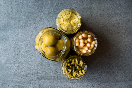 Jars of Pickled Vegetables Green and White Asparagus, Artichoke Heart and Unripe Green Almond...