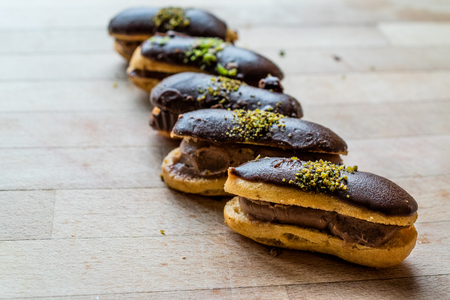 French Dessert Chocolate Eclairs with Cream Filled and Pistachio Powder / Profiteroles. Traditional...