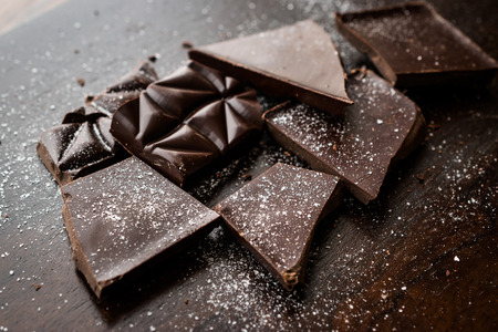 Bitter Chocolate Pieces with Sea Salt on Dark Wooden Surface. Organic Snacks.