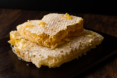 Fresh Honeycomb Slices with Honey on Dark Wooden Board. Organic Food.の写真素材
