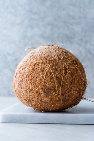 Fresh Organic Brown Raw Coconut on White Marble Board. Organic Food.の写真素材